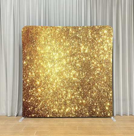 Gold glitter photo booth backdrop on a stand in front of white drapery