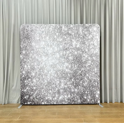 Silver glitter photo booth backdrop standing on a wood floor